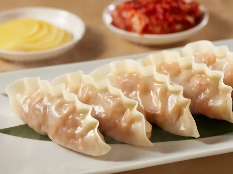Steamed crimped dumplings arranged on leaf‑lined white plate at China Moon, a Chinese Restaurant in Twinsburg